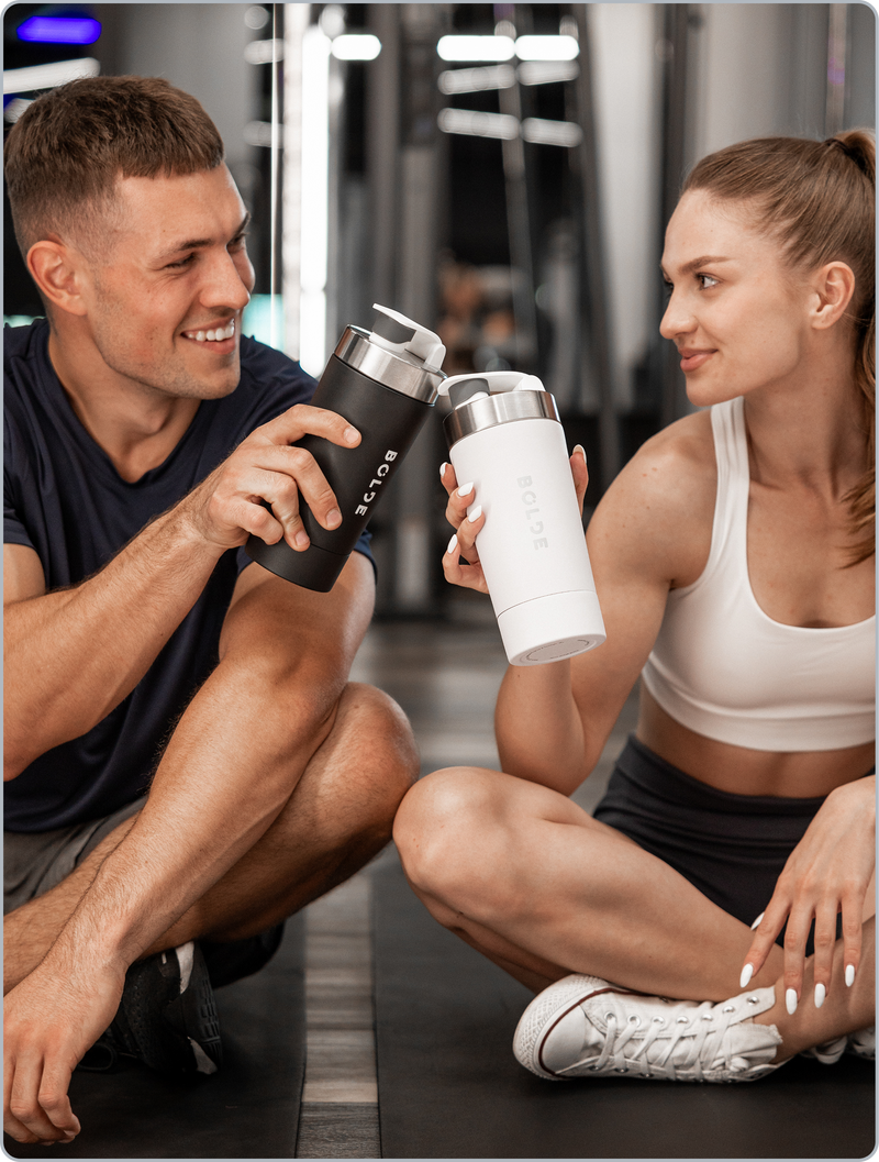 Two athletes holding BOLDE stainless steel shaker bottles at the gym