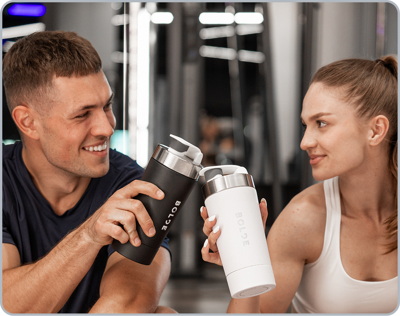 Two athletes holding BOLDE stainless steel shaker bottles at the gym